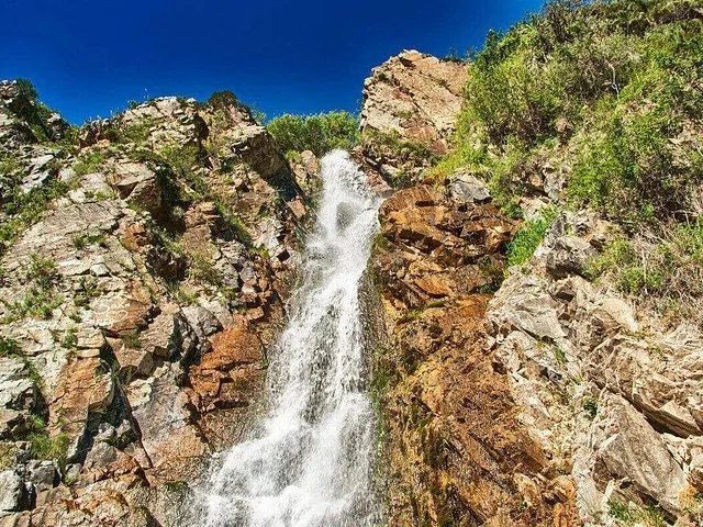 Waterfall flowing down a rugged, rocky cliff face.