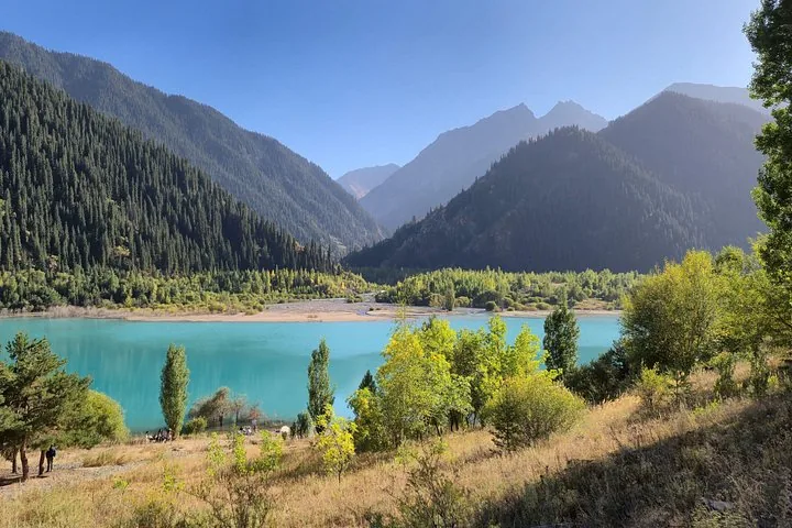 Vredig uitzicht op het Issykmeer, omringd door beboste bergen en een heldere lucht.