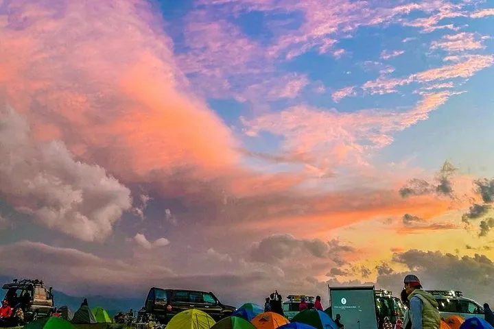 Campingszene im Assy-Plateau mit bunten Zelten unter einem leuchtenden Sonnenuntergang.